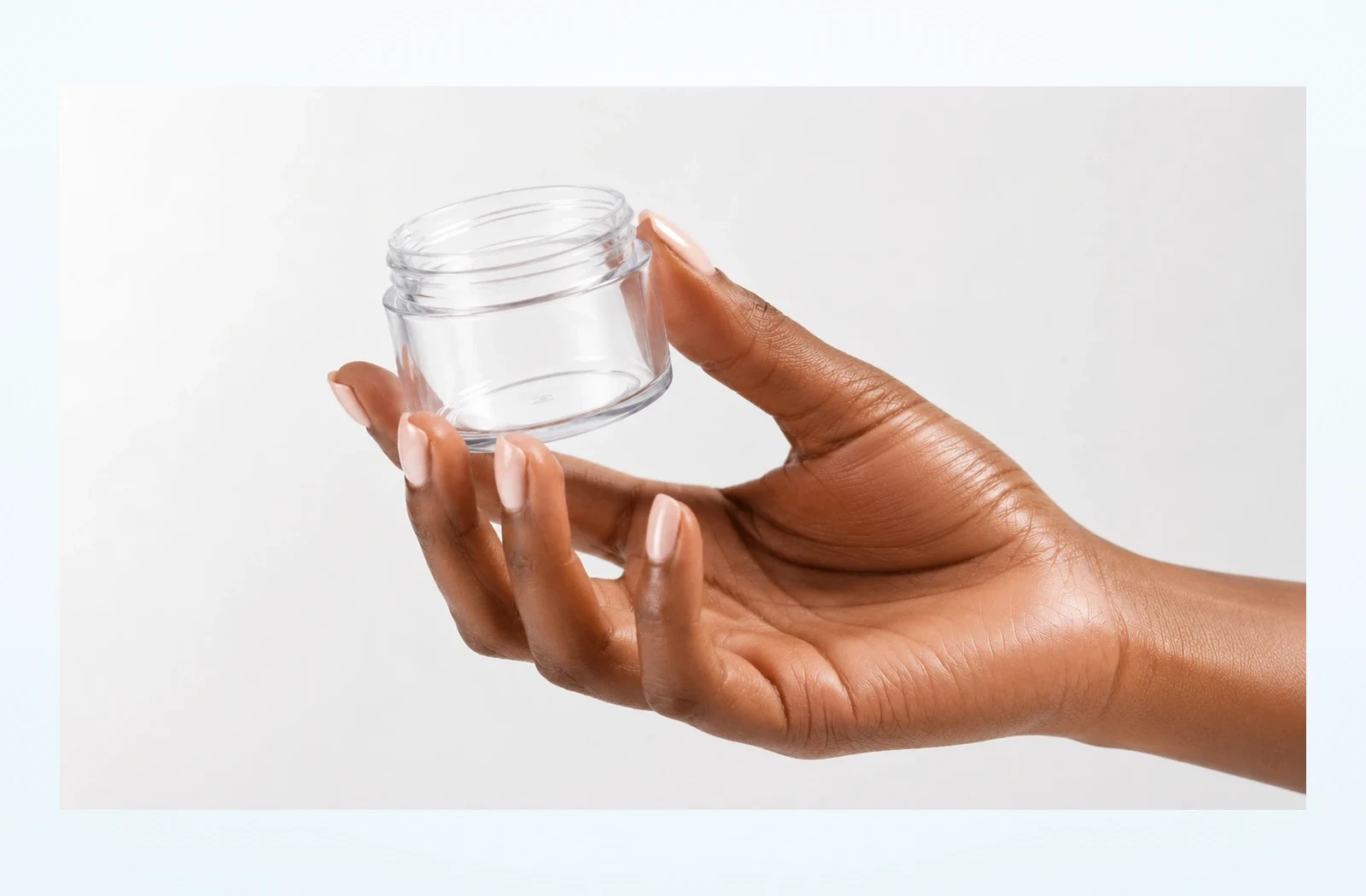 Transparenter PET-Tiegel in einer Hand von rechts